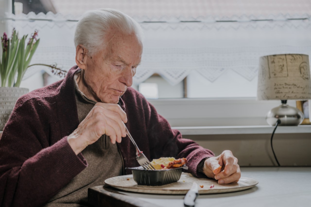 Ein älterer Mann isst ein Fertiggericht