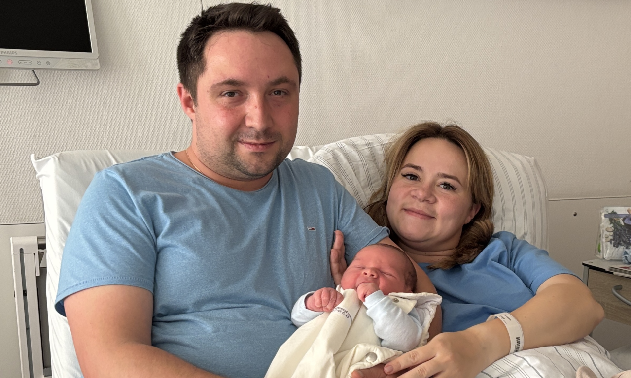 Die glücklichen Eltern mit ihrem Neugeborenen im Arm. 